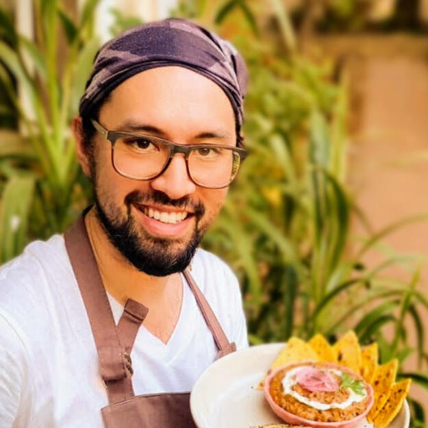 Chef David holding a plate of food smiling at the camera